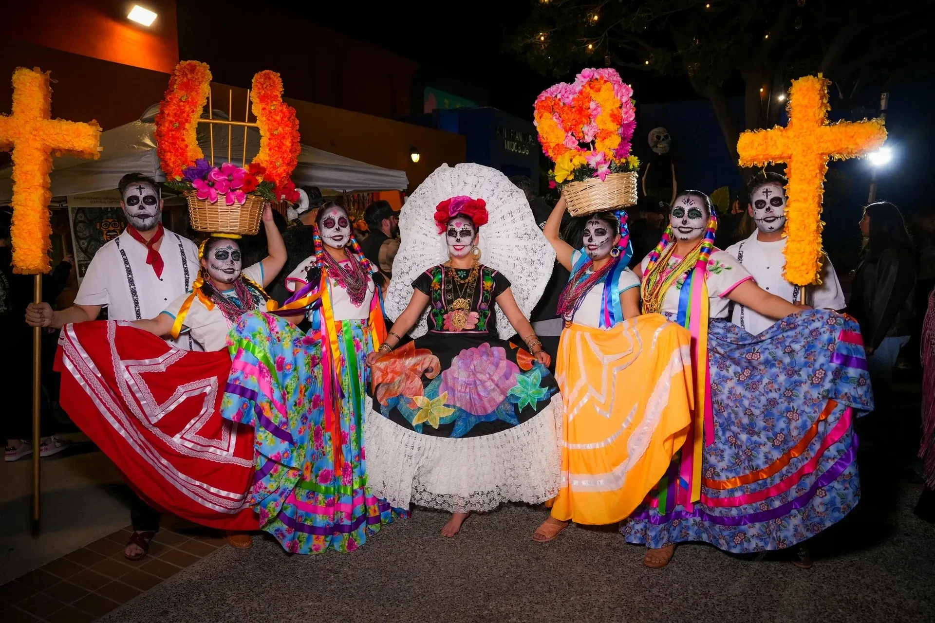 El Velorio participants in colorful traditional dresses and Día de los Muertos face paint.