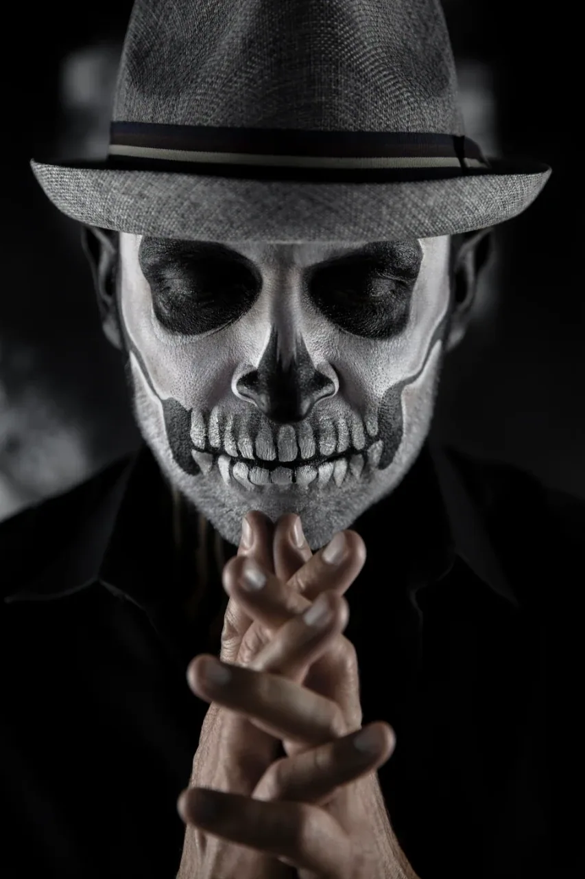 El Velorio portrait with Día de los Muertos skull face paint and a hat.